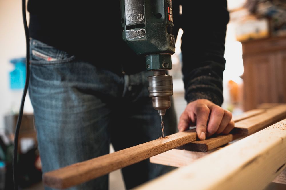 Menuisier perçant une pièce de chêne à l'atelier